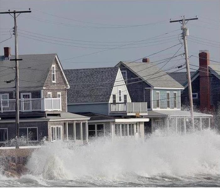 high waves crashing in to homes by a beach