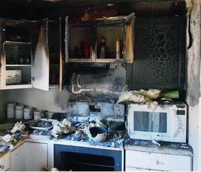 A kitchen covered in smoke and soot damage after a fire