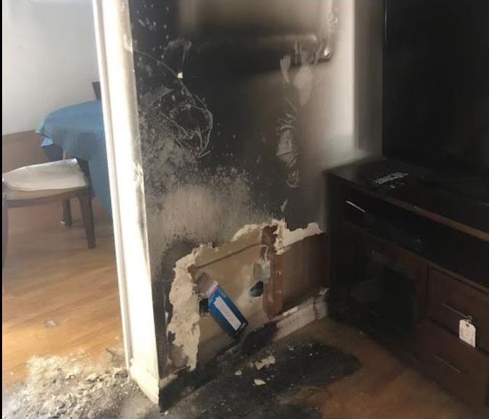Fire damaged room; smoke and soot on wall, floor charred