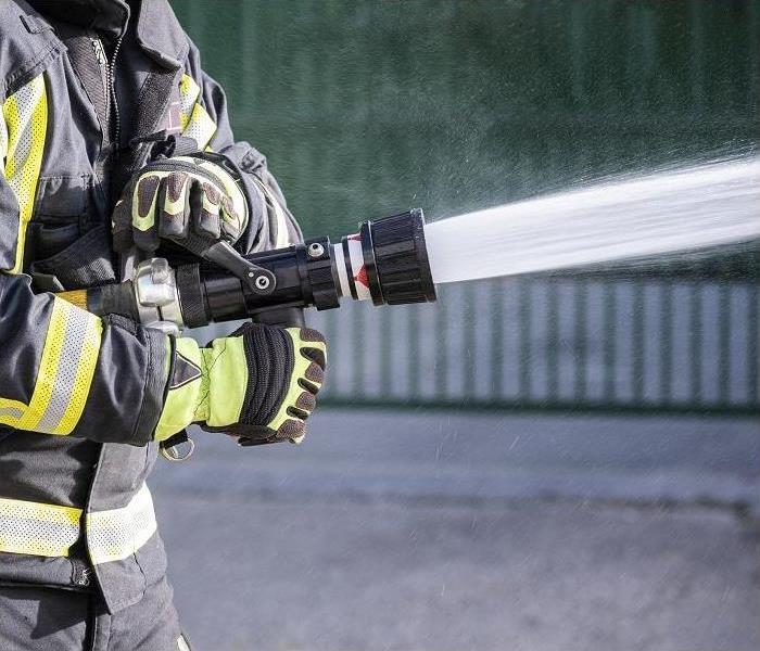 close up of fireman's hand holding fire hose; water coming out
