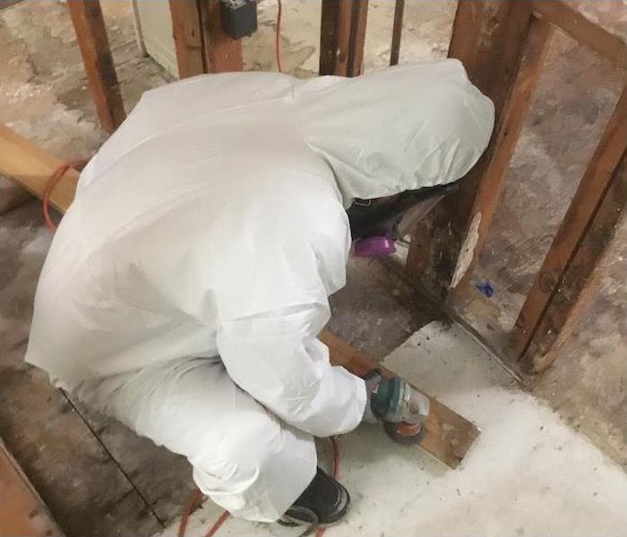 SERVPRO technician in PPE working on wood framing